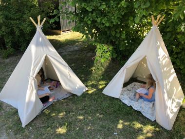Børn der sidder og læser i telte på legepladsen